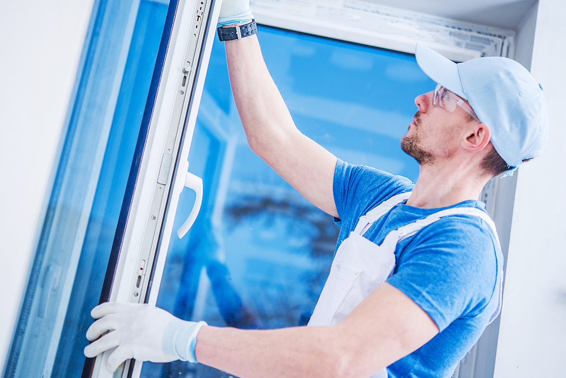 Sanierungsmaßnahmen: Bauarbeiter installiert neues Fenster.