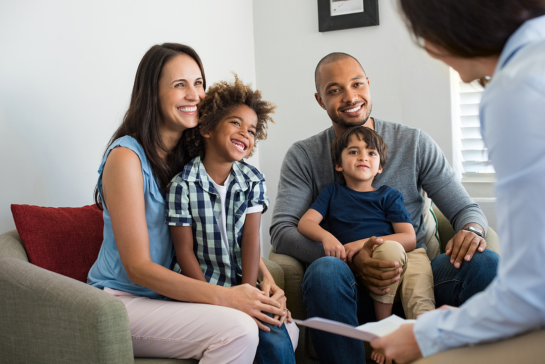 Familie mit zwei Kindern im Gespräch mit einem Finanzierungsexperten