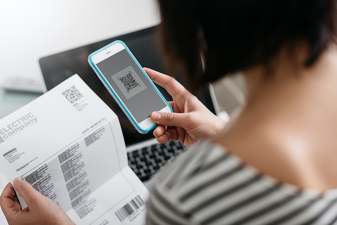 Eine Frau checkt ihre Stromrechnung und bezahlt diese mit dem Smartphone